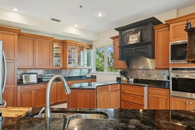 a kitchen with stainless steel appliances granite countertop a stove a sink and a microwave