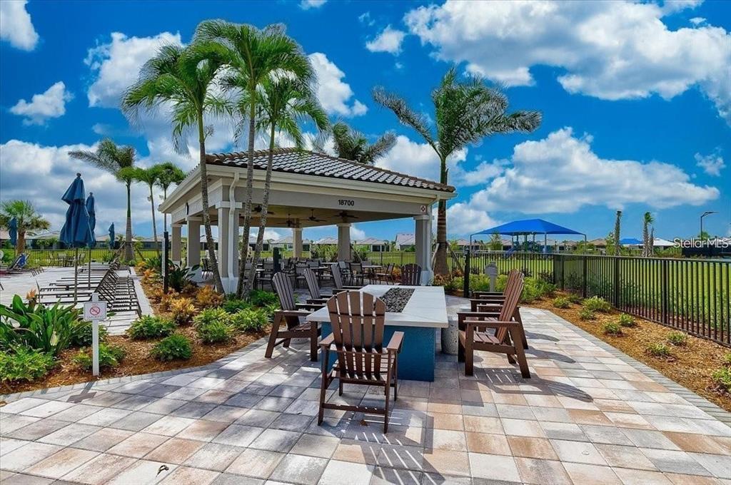 13856 RINUCCIO Street Venice, FL 34293 - Photo 57 of 63 a view of a patio with a dining table and chairs with a fire pit