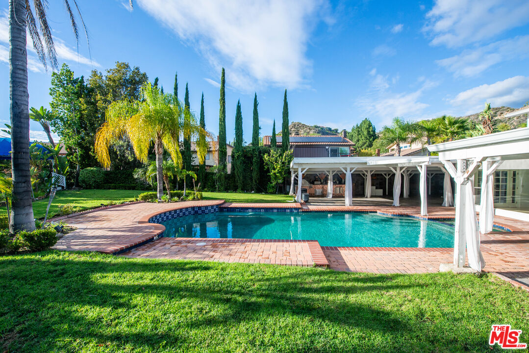 11753 Castillo Lane Porter Ranch, CA 91326 - Photo 4 of 44 a view of swimming pool with lawn chairs and large trees
