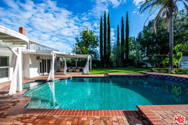 a view of swimming pool with lawn chairs and plants