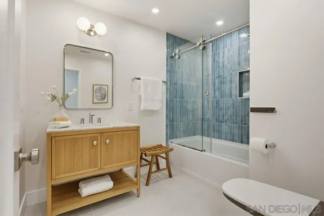 a bathroom with a bathtub shower sink mirror and toilet