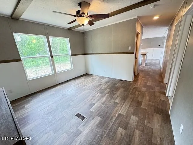 an empty room with wooden floor fan and windows