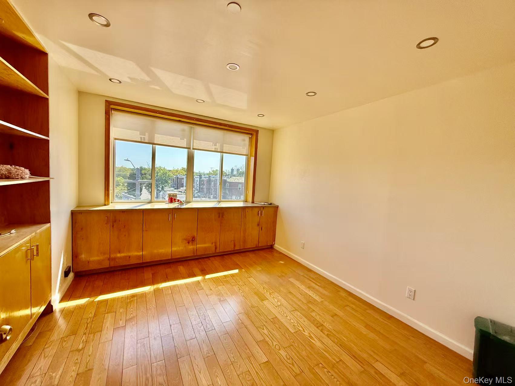 58-04 Main Street, Unit 2D Queens, NY 11355 - Photo 2 of 9 an empty room with wooden floor and windows