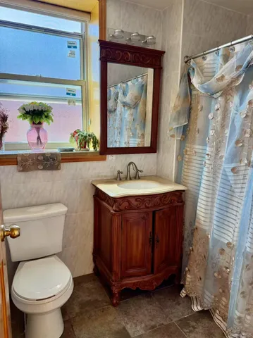 a bathroom with a granite countertop toilet sink and mirror
