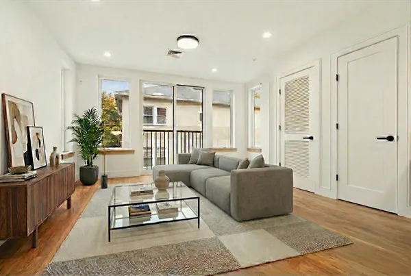 a living room with furniture a flat screen tv and a window