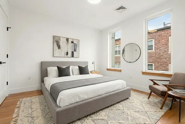 a bedroom with a bed a mirror and a large window