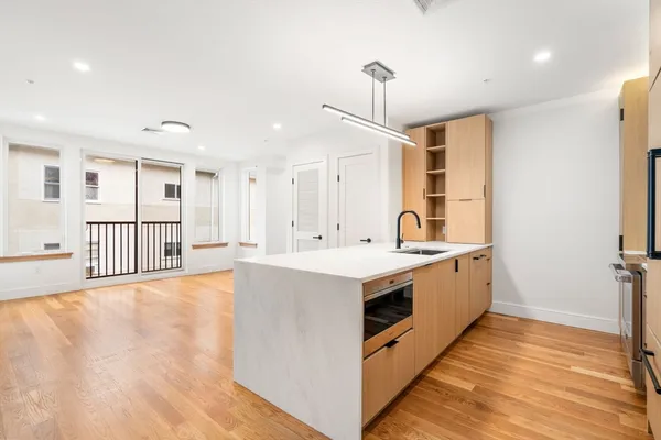 a large white kitchen with wooden floor and a sink