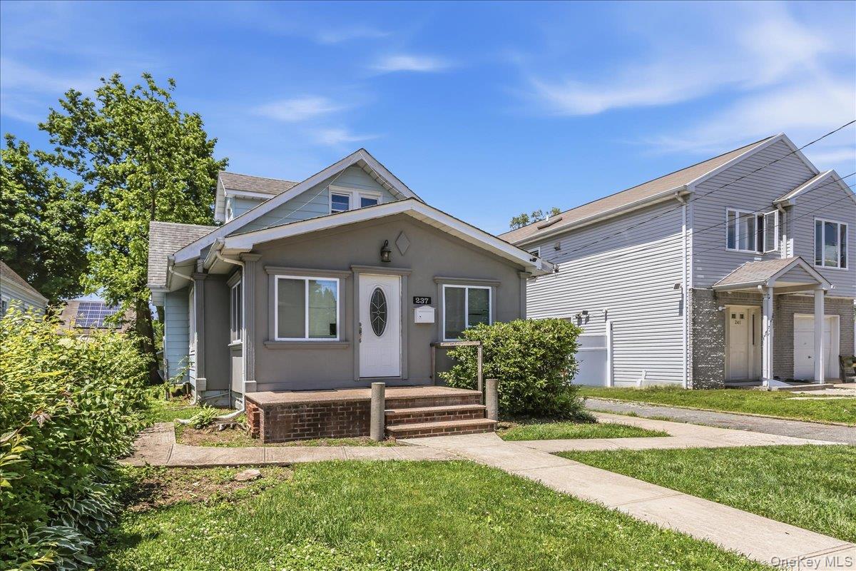 237 Rhodes Avenue Hempstead, NY 11550 - Photo 2 of 24 a front view of a house with a yard