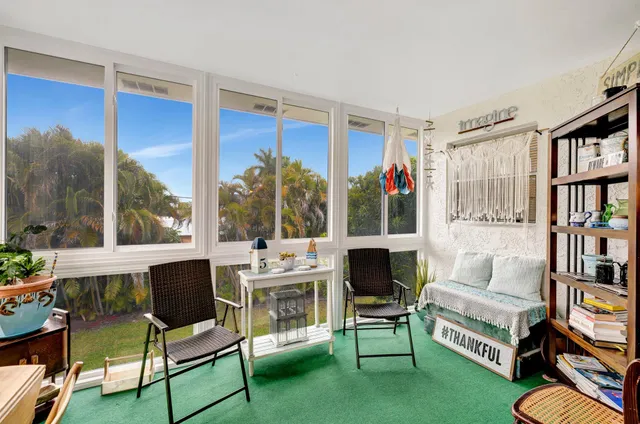 a living room with furniture a bookshelf and a large window