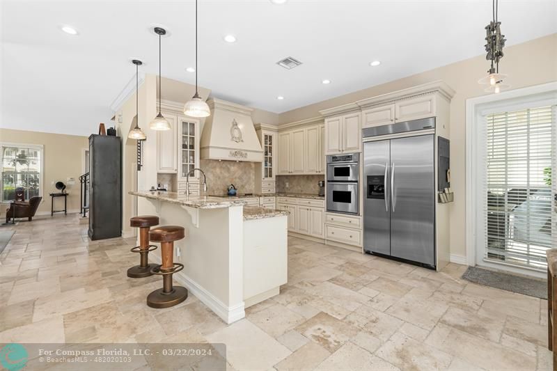 a kitchen with stainless steel appliances kitchen island granite countertop a refrigerator a oven and a sink