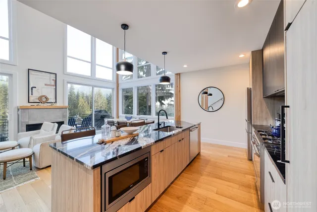 a living room with stainless steel appliances granite countertop a sink and a large window