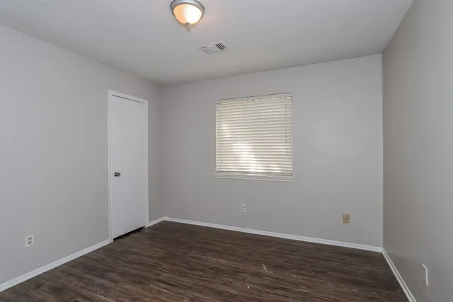 an empty room with wooden floor and windows