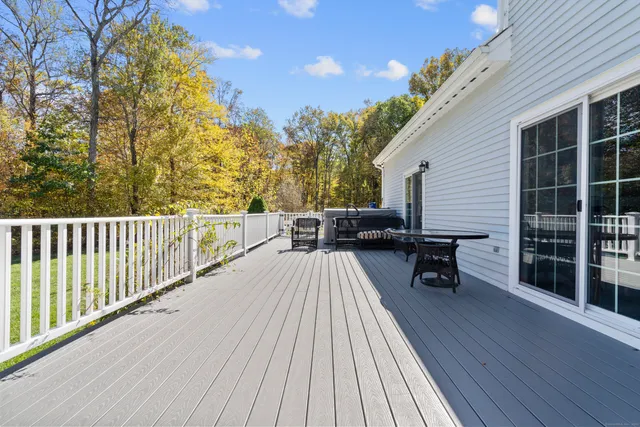 a view of a roof deck with table and chairs a barbeque with wooden floor and fence