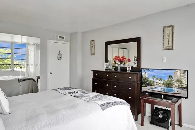 a bedroom with a bed dresser and painting on the wall