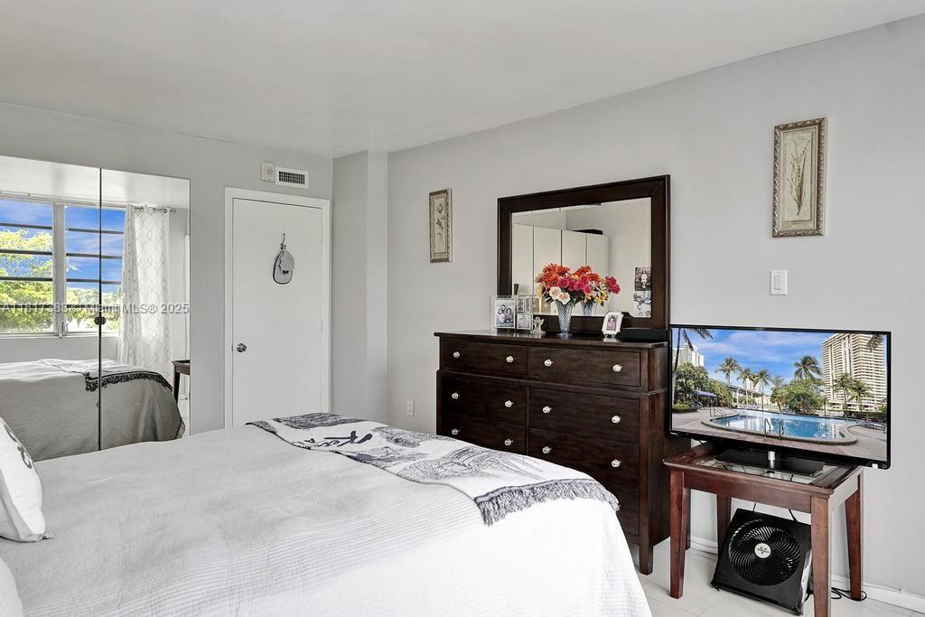 1780 Northeast 191st Street, Unit 4092 Miami, FL 33179 - Photo 16 of 22 a bedroom with a bed dresser and painting on the wall