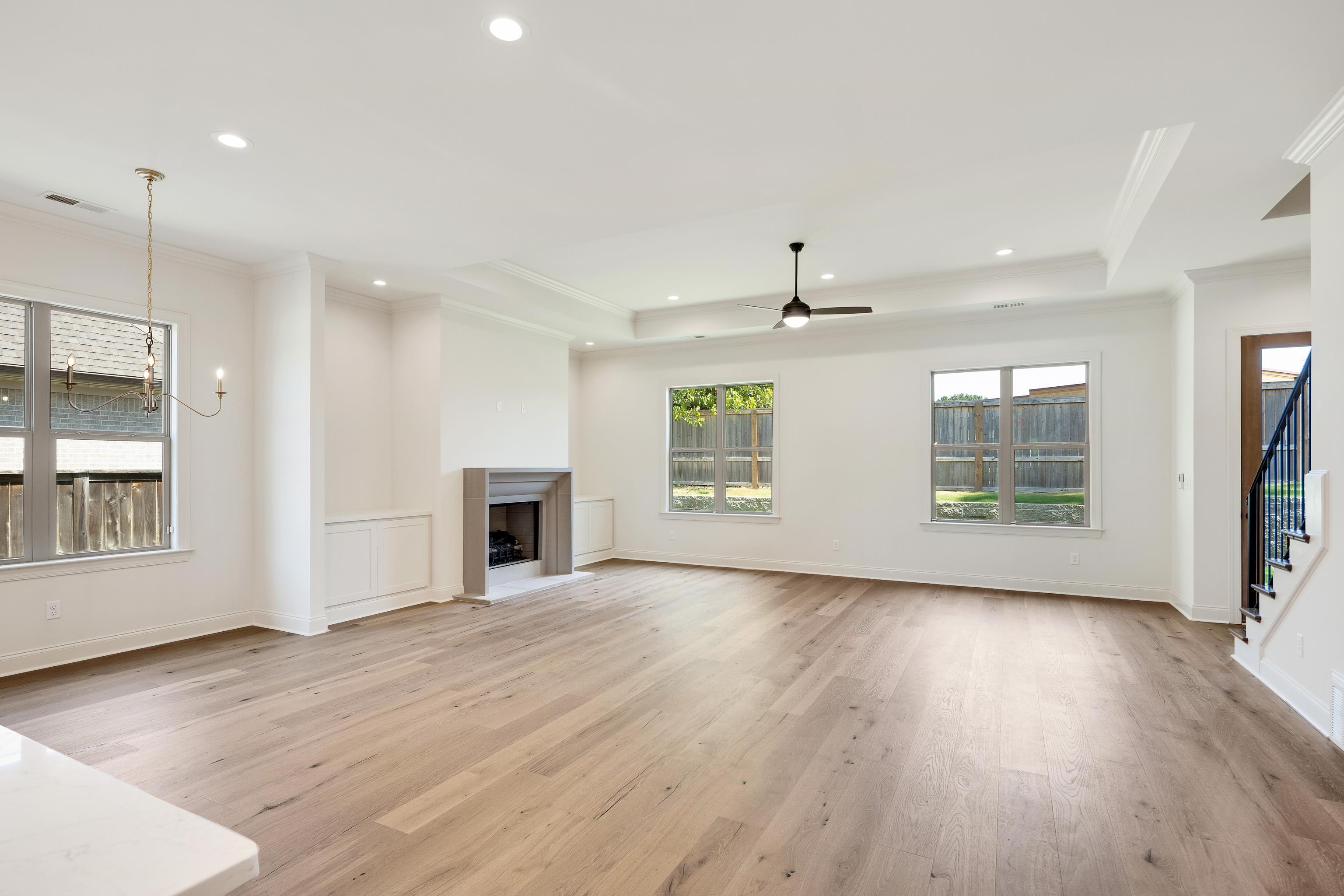 3406 Village Cross Loop Collierville, TN 38017 - Photo 12 of 40 Spacious living area featuring wood-finish flooring, a fireplace with a stone surround, built-in cabinetry, recessed lighting, and a ceiling fan