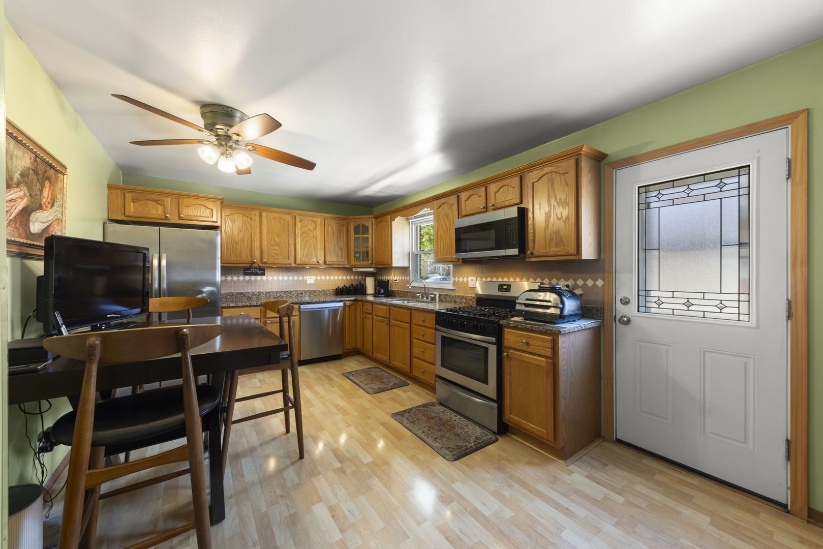 5628 Hawthorne Avenue Berkeley, IL 60163 - Photo 6 of 18 a kitchen with stainless steel appliances granite countertop a stove top oven a sink dishwasher a dining table and chairs with wooden floor