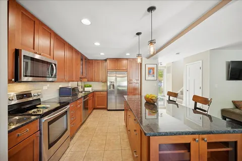 a large kitchen with stainless steel appliances granite countertop a sink counter space cabinets and a stove