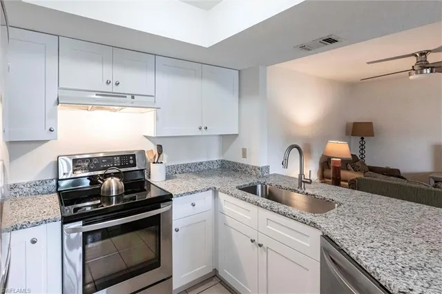 a kitchen with granite countertop a sink stainless steel appliances and cabinets