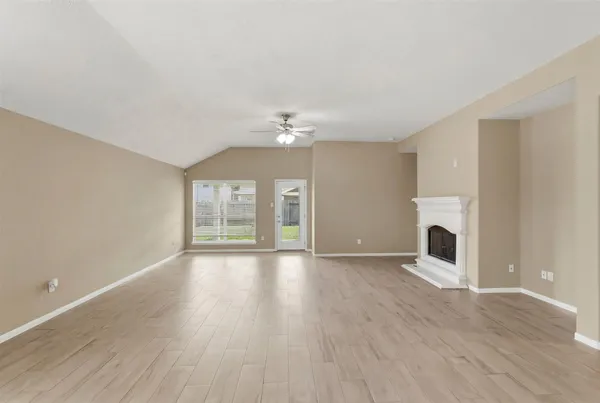 a view of an empty room with window and wooden floor