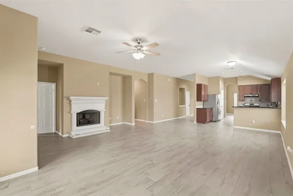 a view of a livingroom with a fireplace a ceiling fan and windows