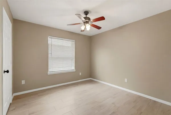 an empty room with a window and a ceiling fan