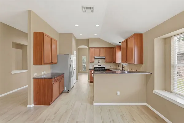 a kitchen with stainless steel appliances granite countertop wooden cabinets a window and a counter space