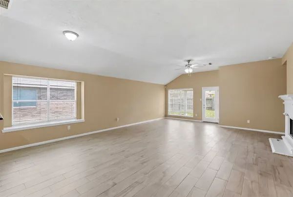 an empty room with wooden floor and windows