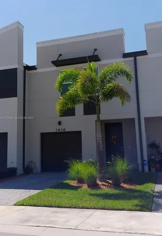a front view of a house with a yard and potted plants