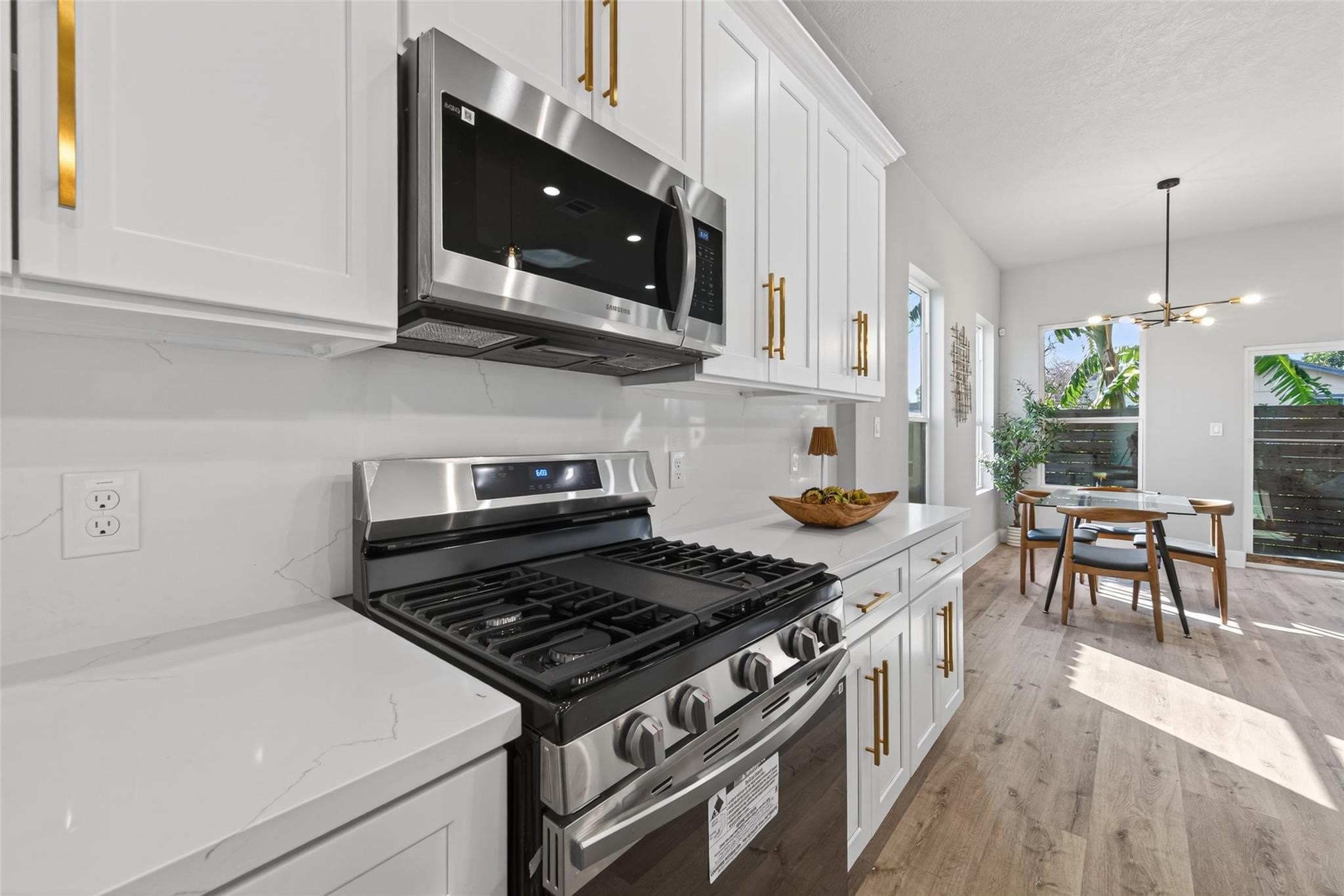 4115 Yale Street Houston, TX 77018 - Photo 11 of 35 Close-up view of premium finishes including quartz countertops, custom cabinetry, and a stainless steel gas range with five burners, paired with a built-in microwave for modern functionality.