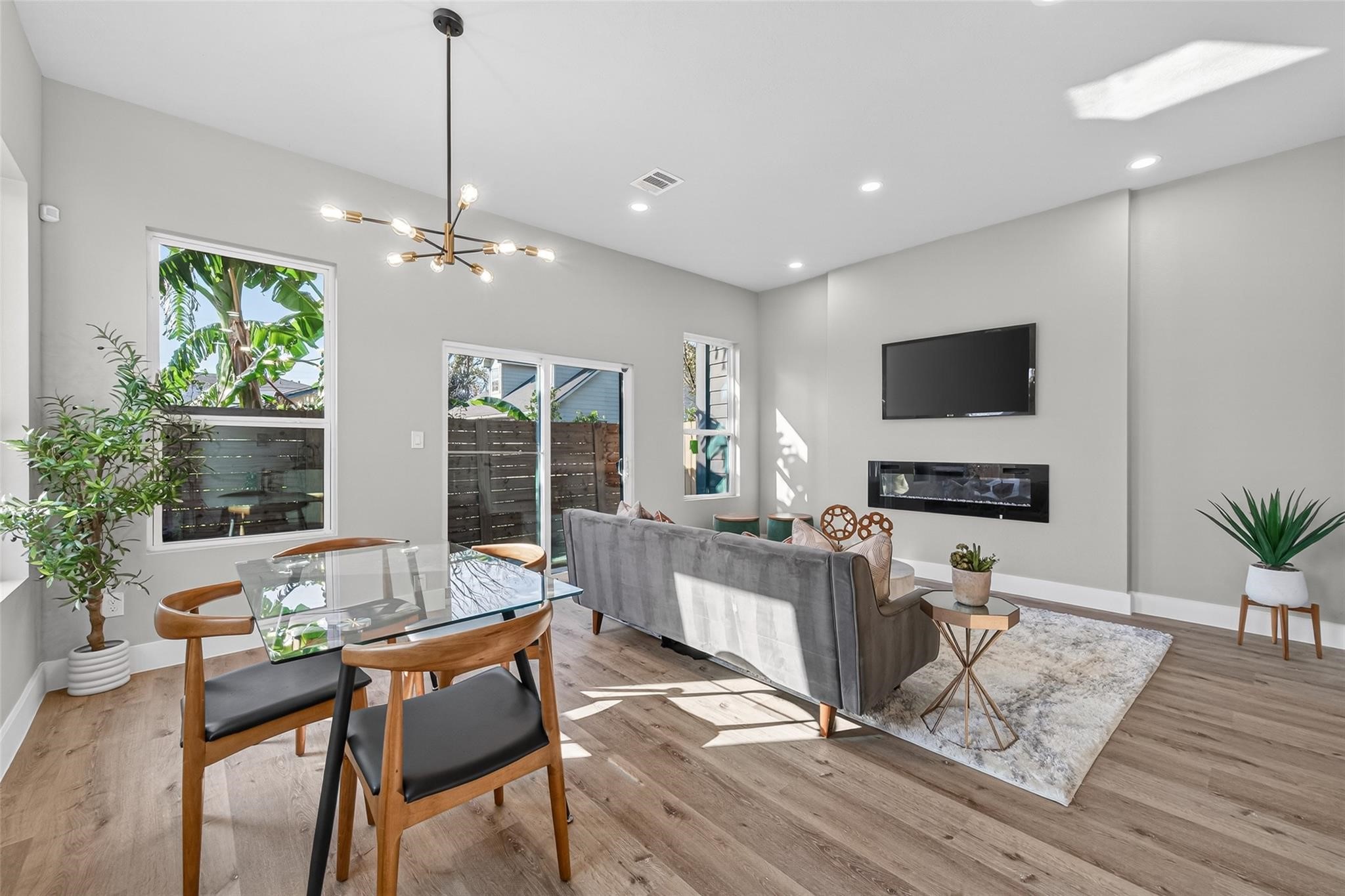 4115 Yale Street Houston, TX 77018 - Photo 17 of 35 Sunlit living and dining space with seamless indoor-outdoor flow, designer lighting fixtures, and durable, low-maintenance plank laminate flooring with a warm white oak finish.