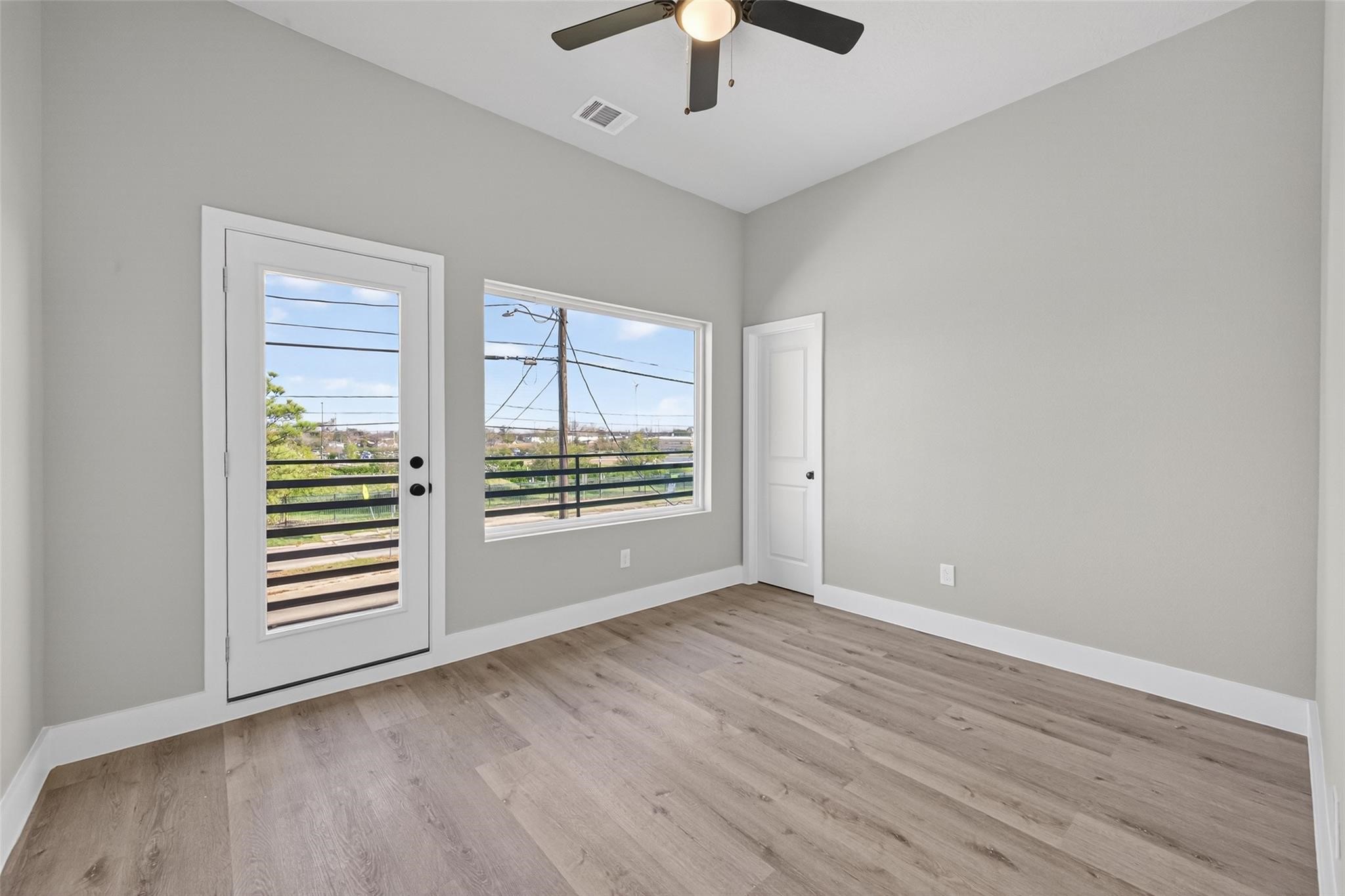 4115 Yale Street Houston, TX 77018 - Photo 23 of 35 Light-filled secondary bedroom featuring white oak–tone plank laminate flooring, a ceiling fan for year-round comfort, and direct access to a private balcony—ideal for guests or a stylish retreat.