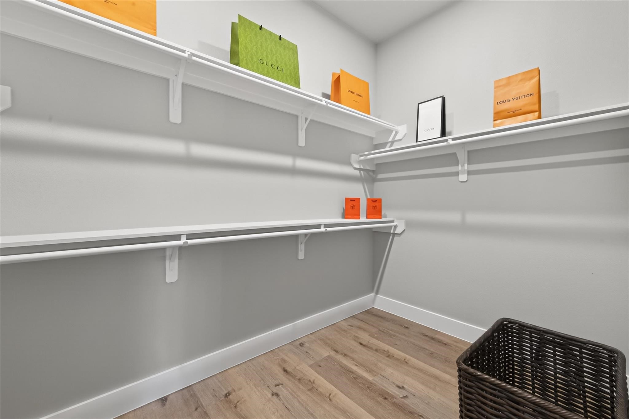 4115 Yale Street Houston, TX 77018 - Photo 33 of 35 Spacious walk-in closet designed for both function and style, offering custom shelving, abundant hanging space, and durable white oak–finish laminate flooring—perfect for an organized, boutique-style wardrobe experience.