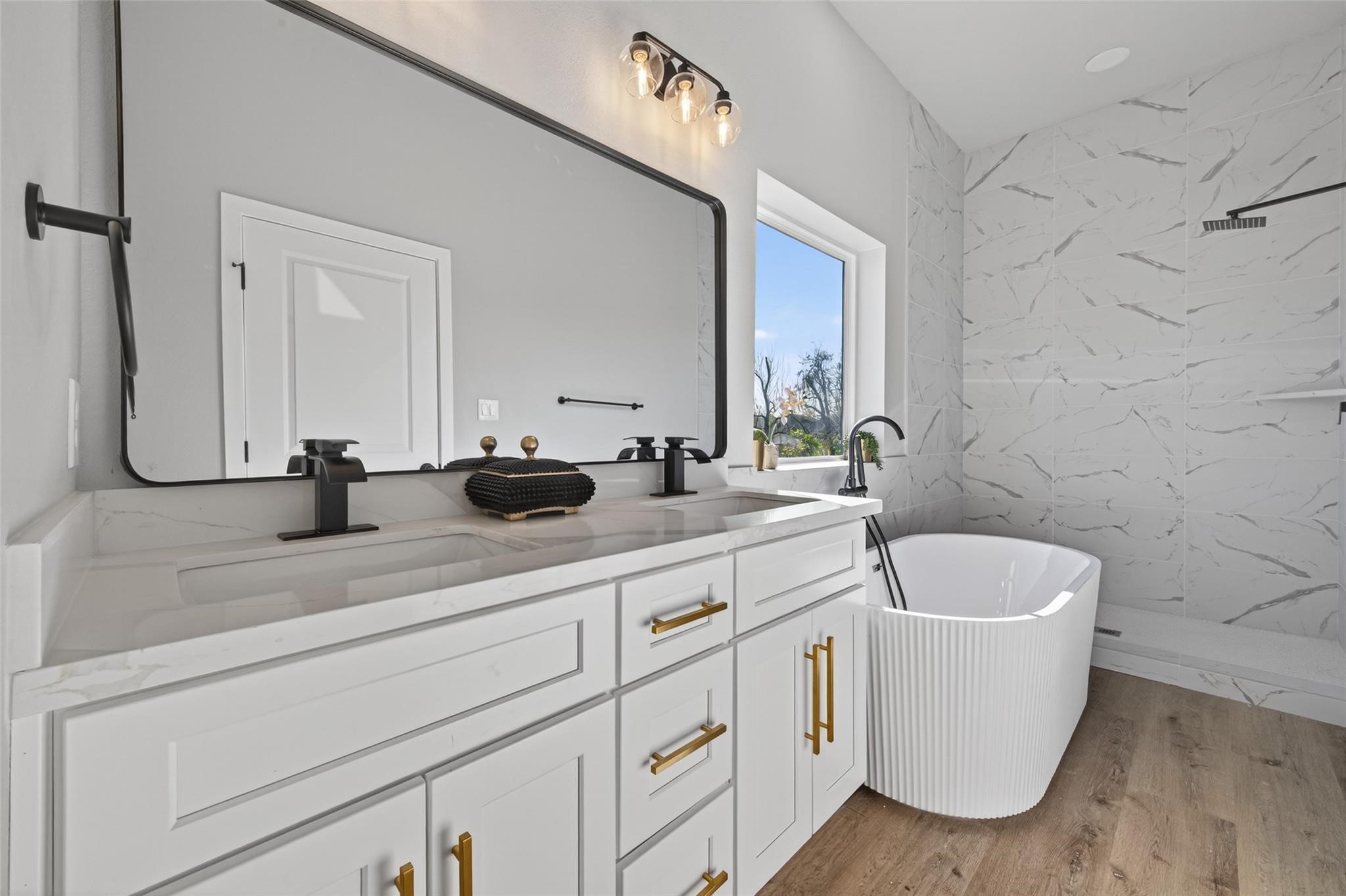 4115 Yale Street Houston, TX 77018 - Photo 34 of 35 Spa-inspired primary bathroom showcasing a custom double-sink quartz vanity with soft-close cabinetry, brushed gold hardware, matte black fixtures, oversized framed mirror, and elegant designer lighting.