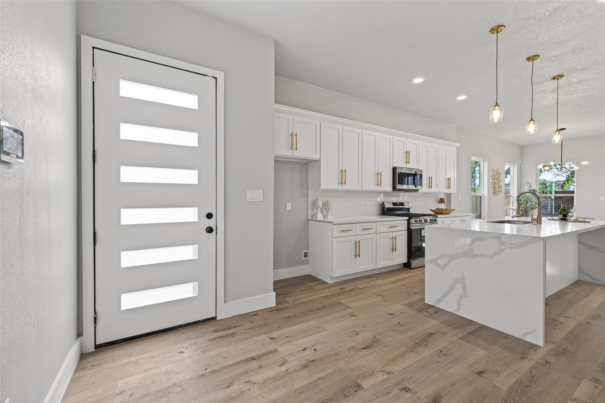 4115 Yale Street Houston, TX 77018 - Photo 5 of 35 Sun-filled entry opens to an expansive open-concept layout featuring white oak–toned plank laminate flooring, smooth contemporary walls, and a modern frosted-glass front door that balances privacy with natural light.