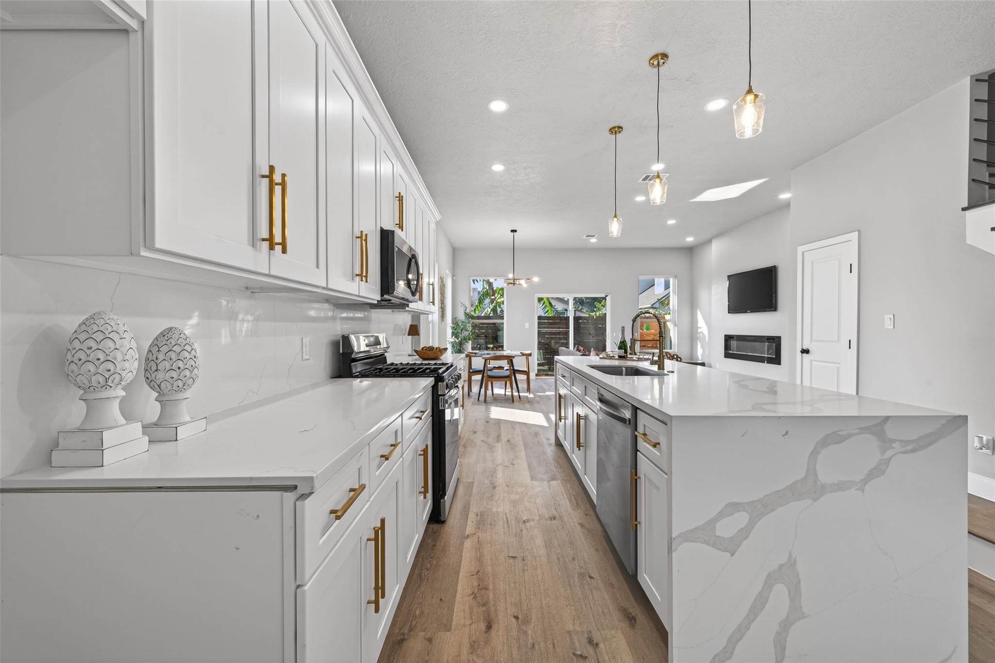 4115 Yale Street Houston, TX 77018 - Photo 7 of 35 Designer kitchen anchored by an oversized quartz waterfall island with dramatic veining, offering generous prep space, seating, and seamless entertaining flow into the living and dining areas.