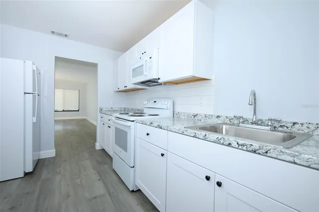 a kitchen with granite countertop a sink and cabinets