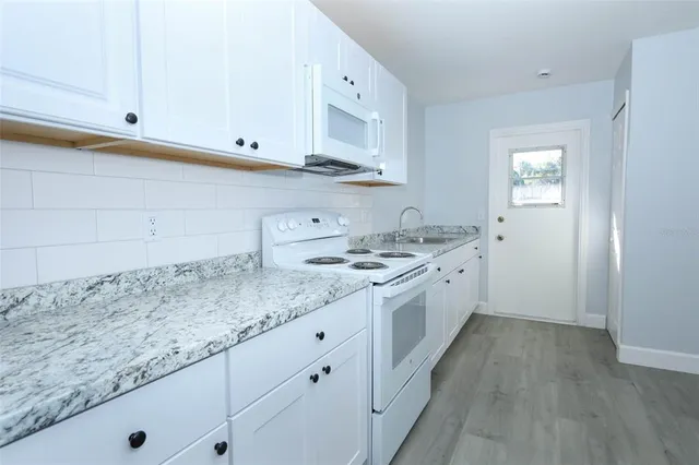 a kitchen with granite countertop white cabinets and white appliances