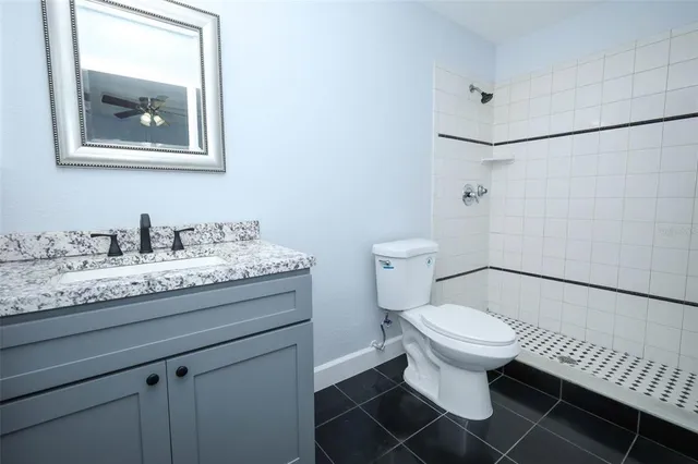 a bathroom with a granite countertop toilet sink and mirror