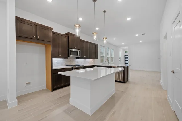 a large kitchen with stainless steel appliances kitchen island a large counter top and a stove top oven