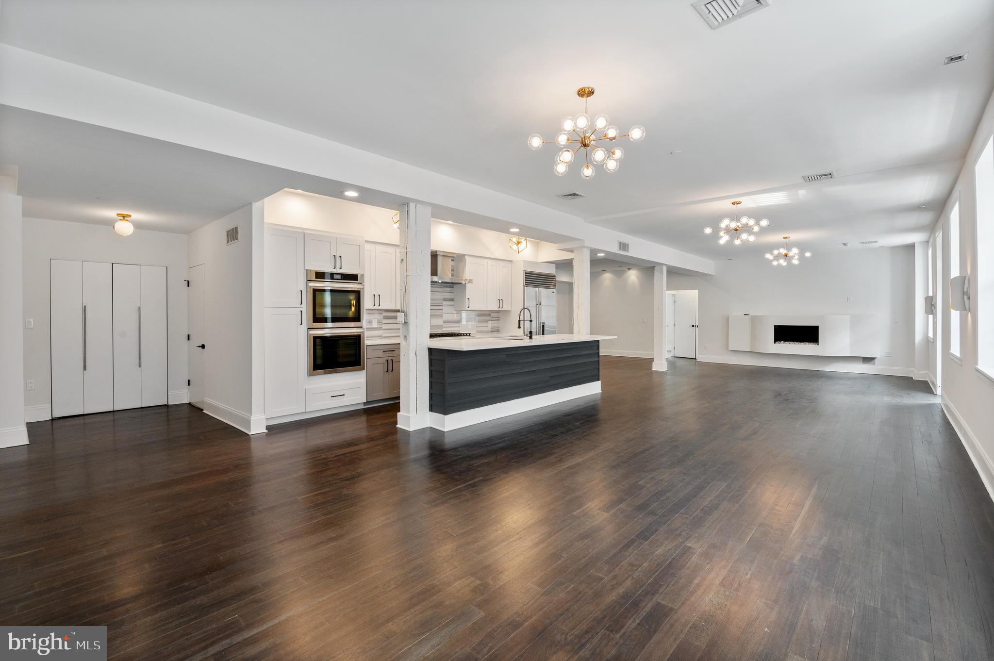 a view of a big room with wooden floor and kitchen