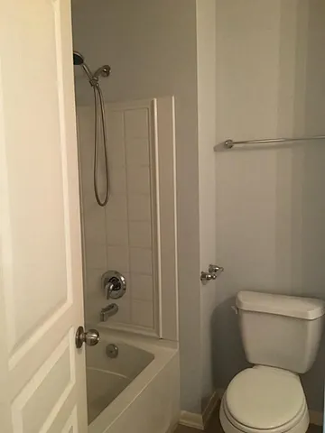 a white toilet sitting next to a bath tub