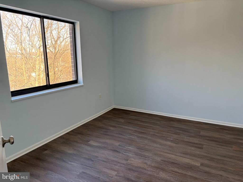 15115 Interlachen Drive, Unit 31020 Silver Spring, MD 20906 - Photo 16 of 48 a view of an empty room with wooden floor and a window
