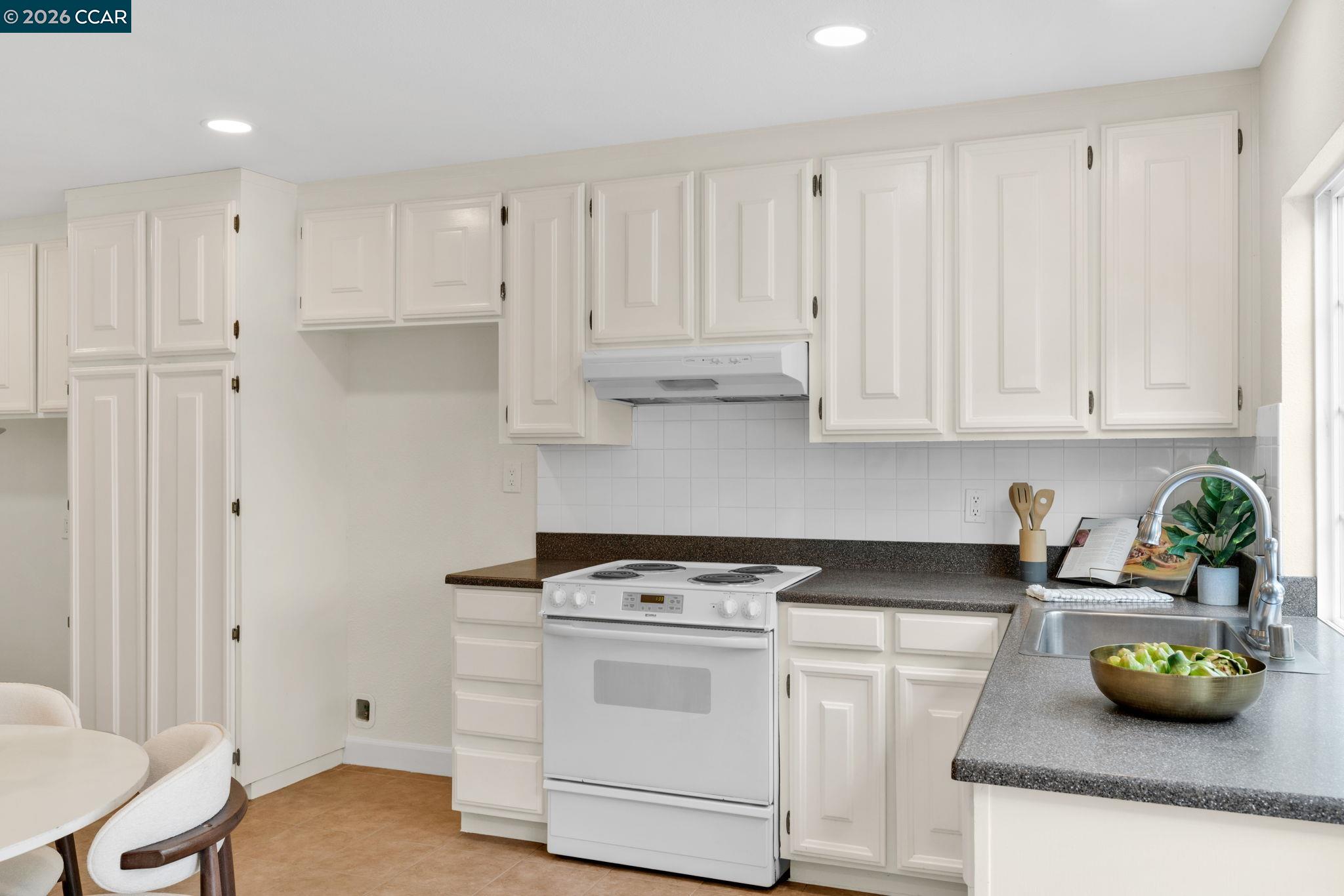 32 Yale Court San Ramon, CA 94583 - Photo 18 of 40 a kitchen with white cabinets and a stove with wooden floor