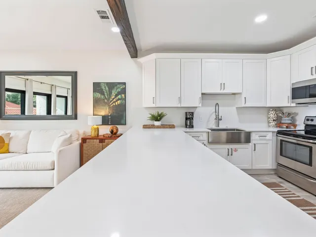 a large white kitchen with cabinets a sink and appliances
