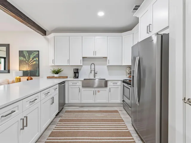 a large white kitchen with wooden floors and white stainless steel appliances