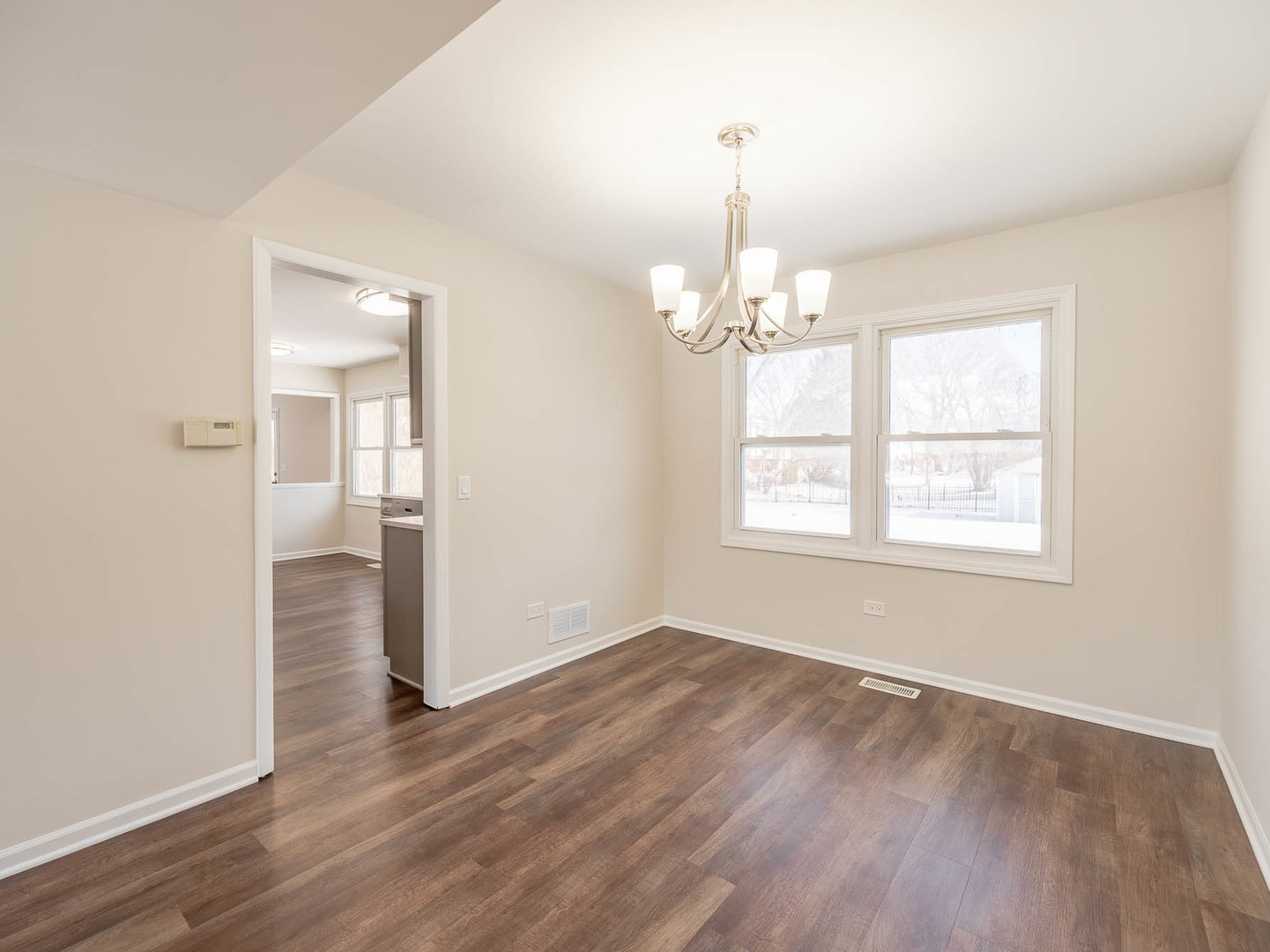 429 6th Street Wheeling, IL 60090 - Photo 5 of 17 an empty room with wooden floor chandelier and windows