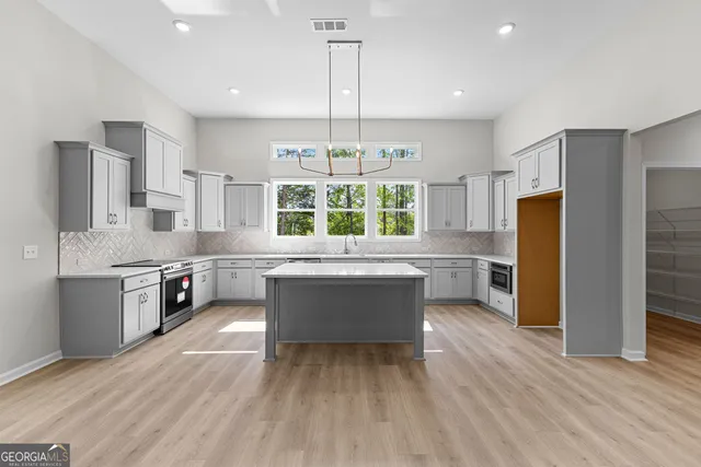 a kitchen with stainless steel appliances granite countertop a refrigerator a sink dishwasher a stove and a dining table with wooden floor