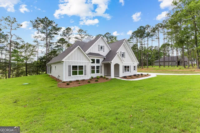 a white house with a big yard and large trees