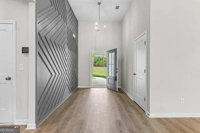 a view of a hallway with wooden floor and a bathroom